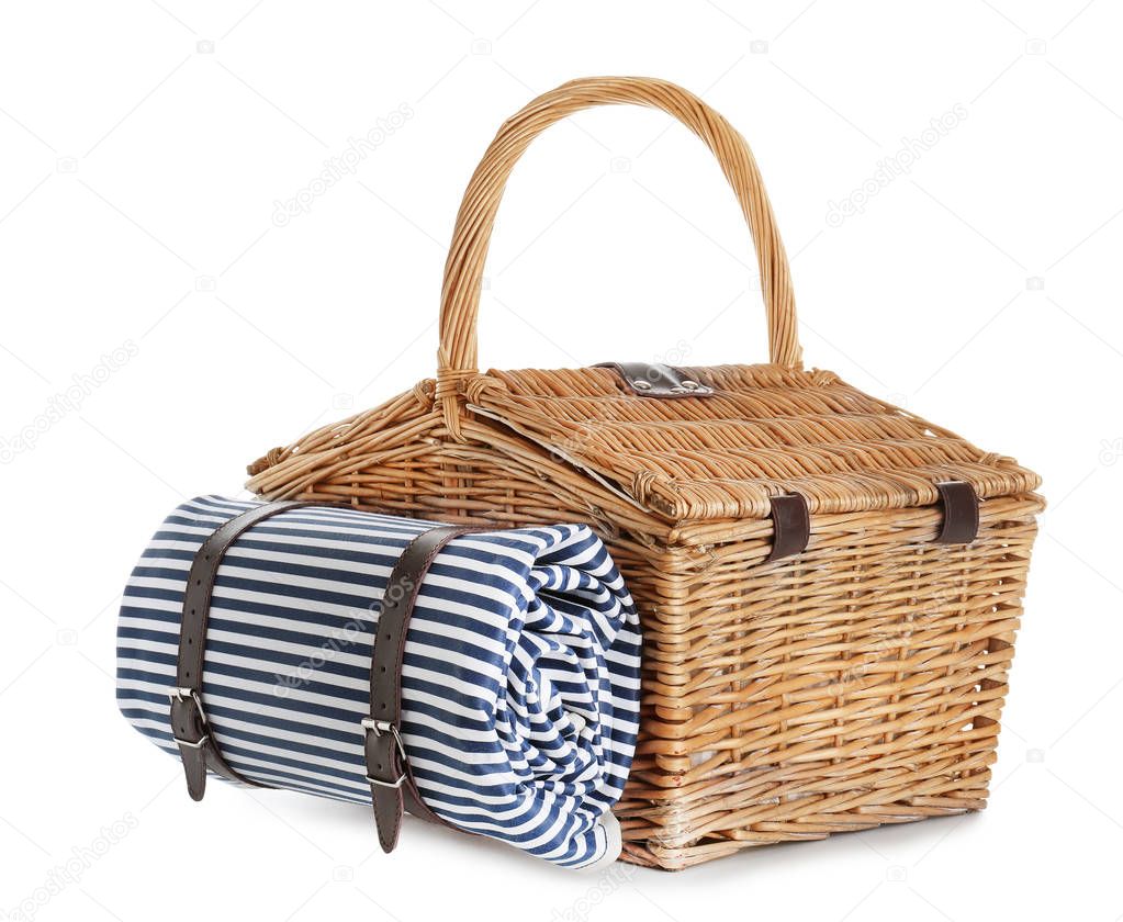 Closed wicker picnic basket with blanket on white background
