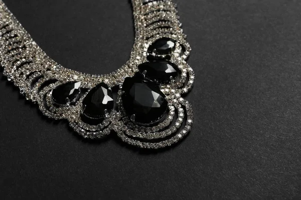 Collier élégant avec pierres précieuses sur fond noir, espace pour le texte. Bijoux de luxe — Photo