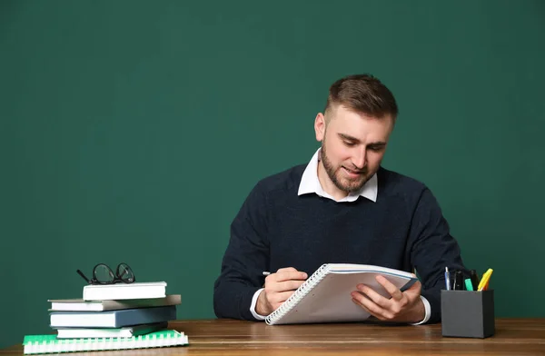 Портрет молодого учителя за столом на зеленом фоне. Пространство для текста — стоковое фото