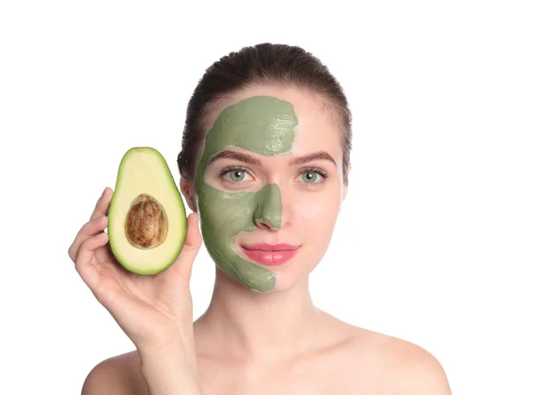Young woman with clay mask on her face holding avocado against white background. Skin care — Stock Photo, Image