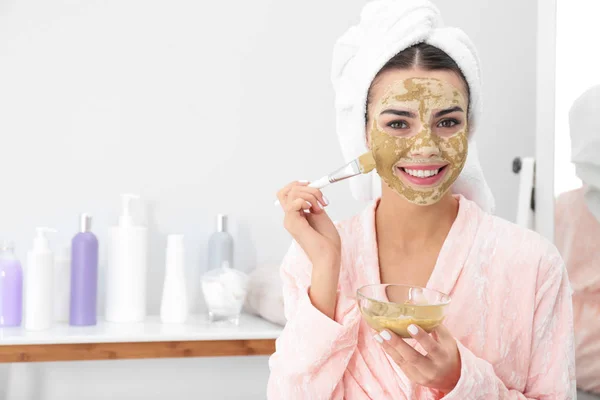 Mladá žena, která používá hliněnou masku na obličeji v koupelně, místo pro text. Péče o pokožku — Stock fotografie