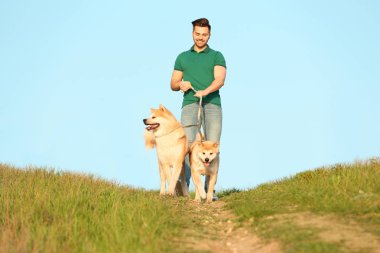 Genç adam onun sevimli Akita Inu köpekler açık havada yürüyüş