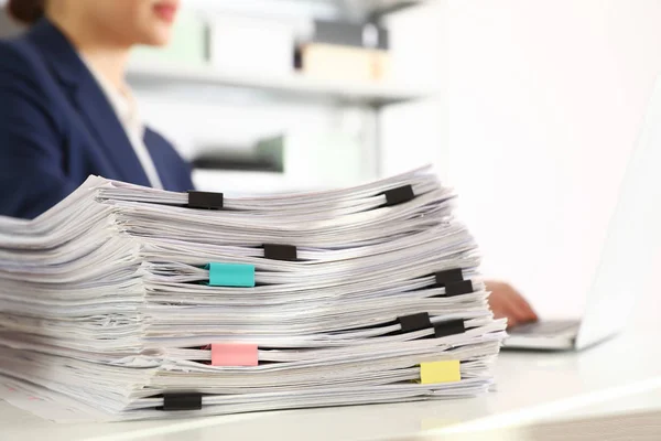 Pilha de documentos e mulher trabalhando com laptop à mesa no escritório, close-up — Fotografia de Stock