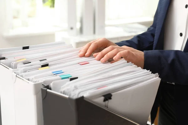 Woman taking documents from folder in archive, closeup — Stock Photo, Image