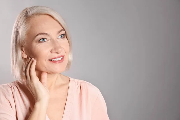 Retrato de mujer madura encantadora con una piel de cara hermosa y saludable y maquillaje natural sobre fondo gris, espacio para el texto — Foto de Stock