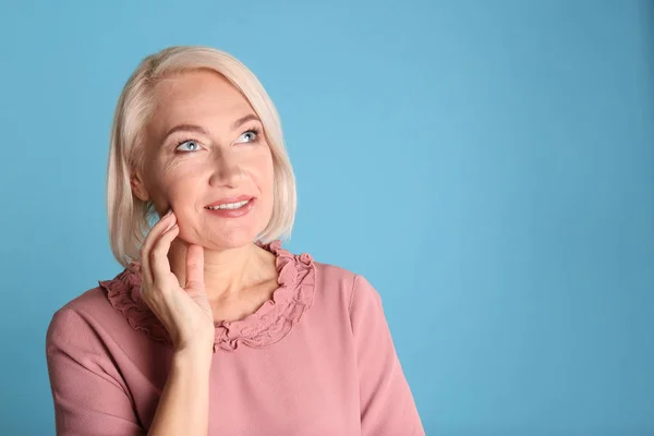 Portret van charmante volwassen vrouw met gezonde mooie gezicht huid en natuurlijke make-up op blauwe achtergrond, ruimte voor tekst — Stockfoto