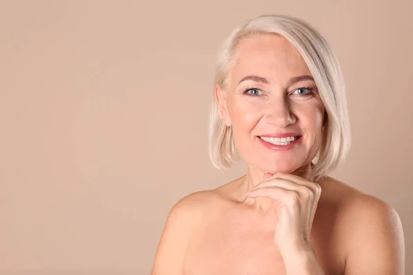 Porträt einer reiferen Frau mit gesunder, schöner Gesichtshaut und natürlichem Make-up auf beigem Hintergrund, Platz für Text — Stockfoto