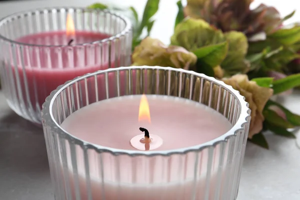 Candele accese e fiori freschi sul tavolo grigio, primo piano — Foto Stock