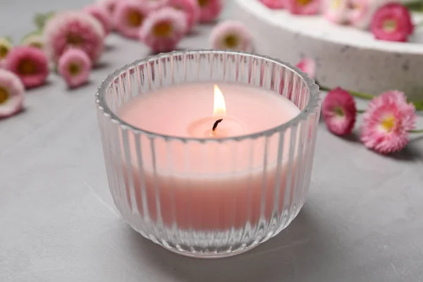 Stylové složení nabídky s hořící svící a květinami na šedém stole. Útulný interiérový prvek — Stock fotografie