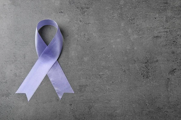灰色の石の背景に紫色のリボン、テキスト用のスペースを持つトップビュー。家庭内暴力に対する意識 — ストック写真