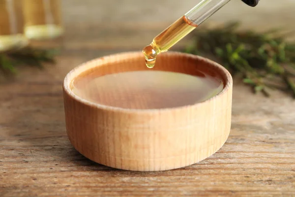 Despejando óleo de árvore de chá natural de garrafa em tigela na mesa, close-up — Fotografia de Stock