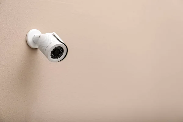 Câmera de segurança CCTV moderna na parede bege. Espaço para texto — Fotografia de Stock
