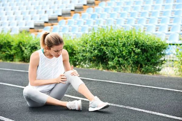 Femme en tenue de sport souffrant de douleurs au genou au stade — Photo