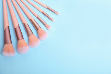 Açık mavi arka plan üzerinde profesyonel makyaj fırçaları seti ile düz yatıyordu kompozisyon. Metin için alan