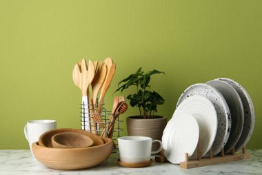 Saksı bitki ve yeşil duvara yakın beyaz mermer masa üzerinde mutfak seti. Modern iç tasarım