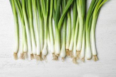 Beyaz ahşap arka plan üzerinde taze yeşil soğan, üst görünümü