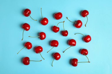 Açık mavi arka plan üzerinde birçok olgun tatlı kiraz, düz yatıyordu