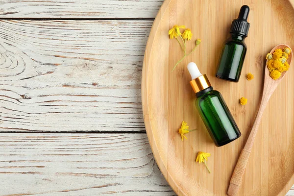 Podnos s láhvemi esenciálního oleje a květů na dřevěném stole. Místo pro text — Stock fotografie
