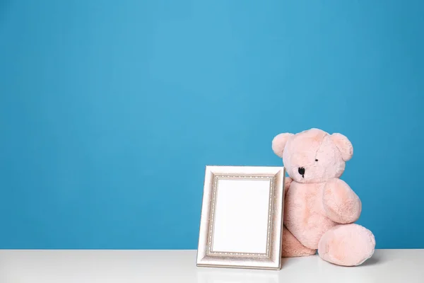 Cadre photo et adorable ours en peluche sur la table sur fond couleur, espace pour le texte. Éléments de chambre enfant — Photo