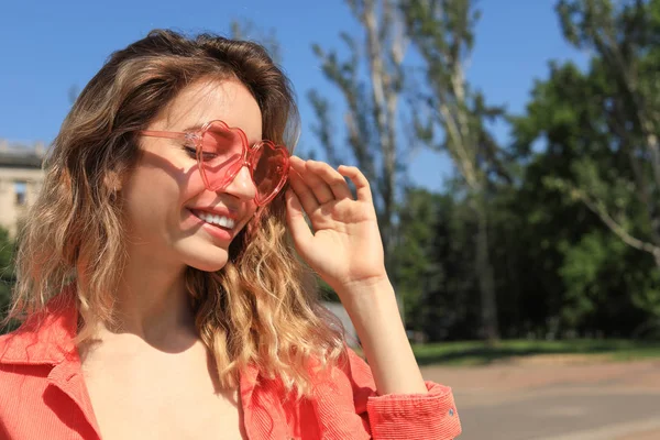 Portrait de femme heureuse avec des lunettes en forme de coeur en ville le jour ensoleillé. Espace pour le texte — Photo