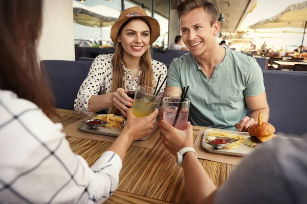 Young people with burgers in street cafe — Stock Photo, Image