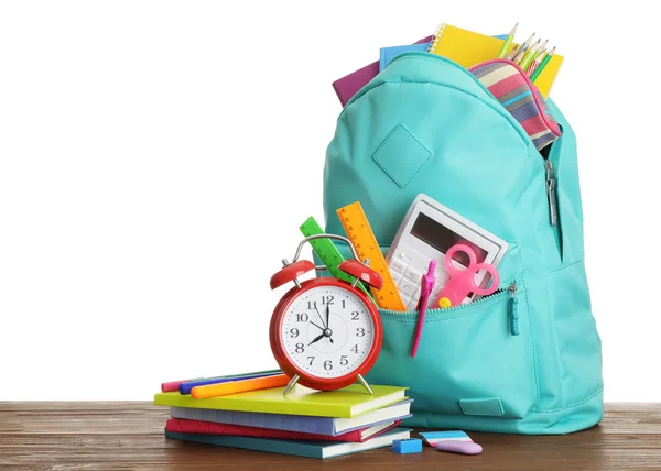 Стильна шкільна сумка з різними стаціонарними годинниками та будильником на дерев'яному столі, білий фон — стокове фото