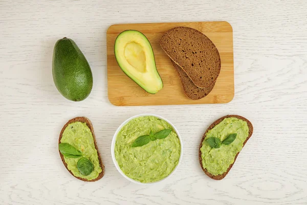 Platte lay compositie met guacamole, sandwiches en avocado's op witte houten tafel — Stockfoto