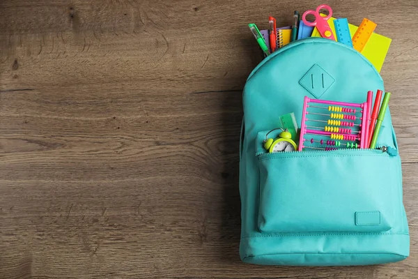 Stylischer Rucksack mit verschiedenen Schulmaterialien auf Holztisch, Draufsicht. Raum für Text — Stockfoto