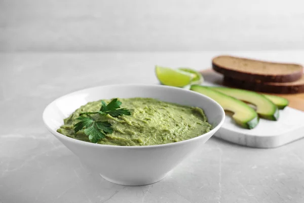 Kom met guacamole gemaakt van rijpe avocado's geserveerd op Lichttafel, ruimte voor tekst — Stockfoto