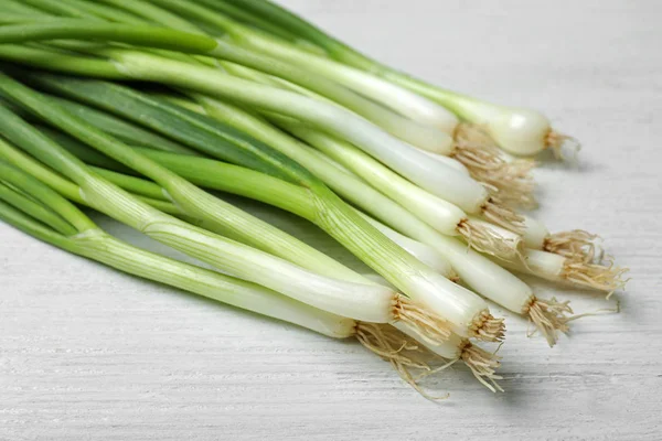 Bunch of fresh green onions on white wooden background, closeup — Stock Photo, Image