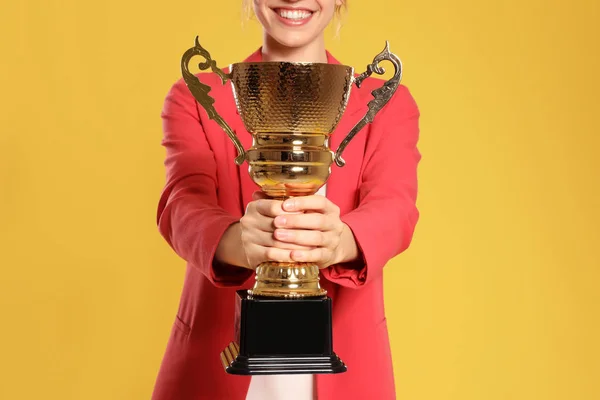 Jonge zakenvrouw met gouden trofee Cup op gele achtergrond, close-up — Stockfoto