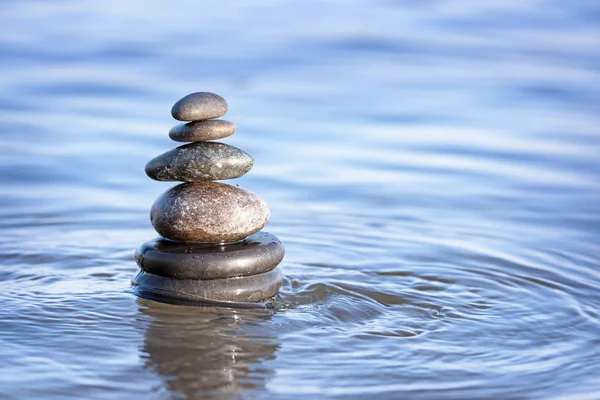 Pilha de pedras escuras na água do mar, espaço para texto. Conceito Zen — Fotografia de Stock