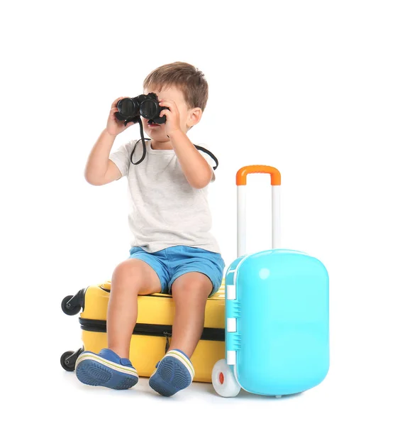 Schattige kleine jongen met verrekijker en koffers op witte achtergrond — Stockfoto