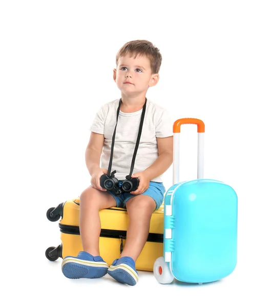 Lindo niño pequeño con binocular y maletas sobre fondo blanco — Foto de Stock
