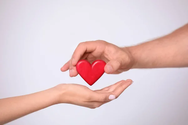 Hombre dando el corazón rojo a la mujer sobre fondo blanco, primer plano. Concepto de donación — Foto de Stock