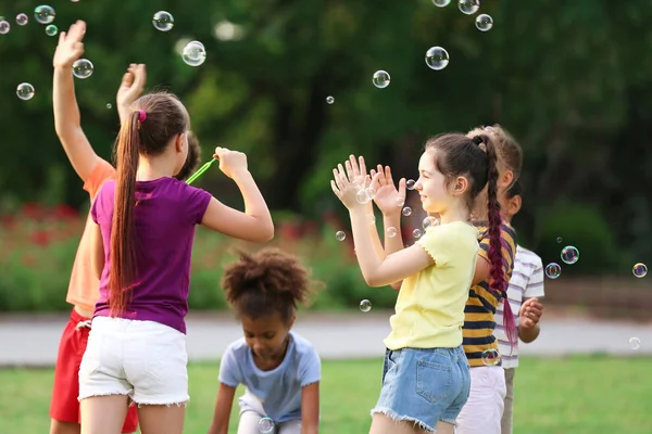 Niedliche kleine Kinder spielen mit Seifenblasen im Park — Stockfoto