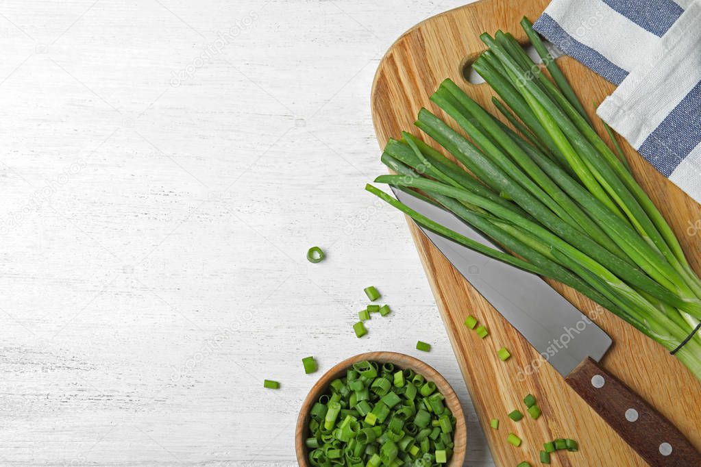 Flat lay composition with fresh green onions on white wooden background. Space for text