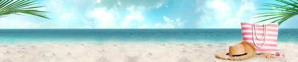 Różne stylowe akcesoria plażowe na piasku w pobliżu oceanu. Przestrzeń do projektowania — Zdjęcie stockowe