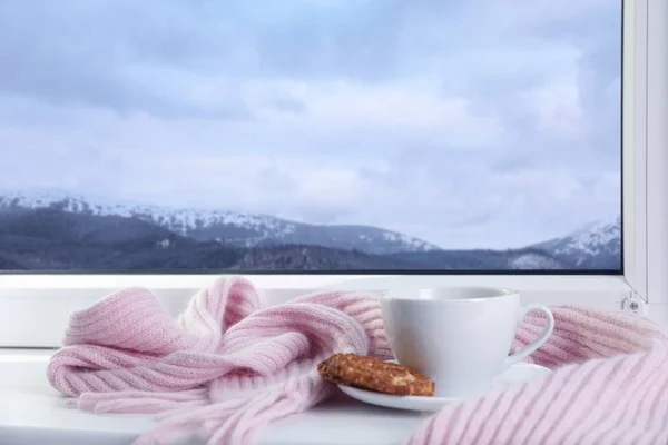 겨울 산악 풍경을 감상할 수 있는 창문 근처의 따뜻한 음료, 쿠키, 스카프 — 스톡 사진