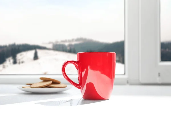 Warme drank en koekjes in de buurt van het raam met uitzicht op de Winterberg landschap — Stockfoto