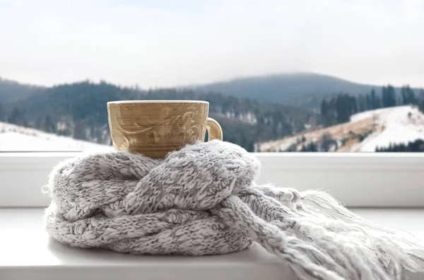 겨울 산의 풍경을 볼 수있는 창문 근처의 따뜻한 음료와 따뜻한 스카프 — 스톡 사진