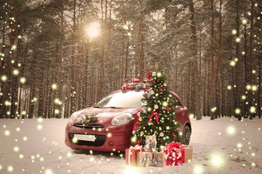 Kış gününde karlı ormanda Noel ağacı yakınında hediyeler ve çelenk ile araba