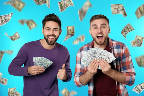 Ευτυχισμένοι νέοι άνδρες με δολάρια κάτω από τη βροχή των χρημάτων σε μπλε φόντο — Φωτογραφία Αρχείου