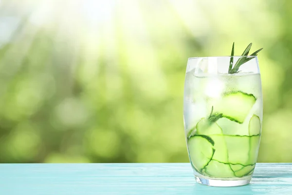 Vaso de bebida refrescante con rodajas de pepino y romero sobre mesa de madera azul sobre fondo borroso, espacio para texto — Foto de Stock