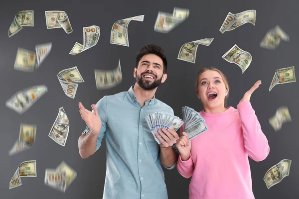 Gri arka plan üzerinde para yağmur altında dolar ile Mutlu genç çift