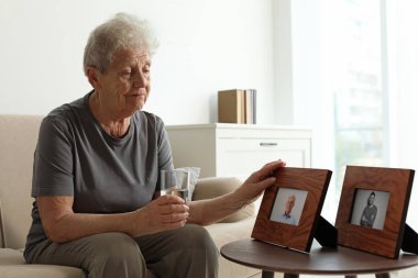 Evde çerçeveli fotoğrafları ile yaşlı kadın