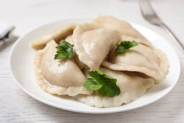 Tallrik med läckra kokta dumplings serveras på vitt träbord, närbild — Stockfoto