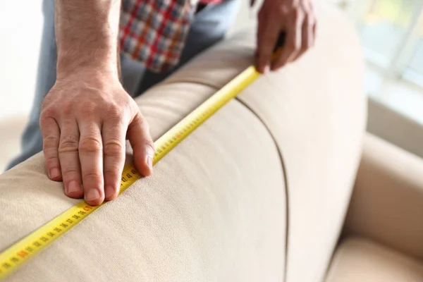 Hombre midiendo sofá beige, primer plano. Herramienta de construcción — Foto de Stock