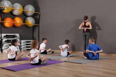 Sevimli küçük çocuklar ve eğitmen okul spor salonunda fiziksel egzersiz yapıyor. Sağlıklı yaşam tarzı