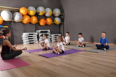 Sevimli küçük çocuklar ve eğitmen okul spor salonunda fiziksel egzersiz yapıyor. Sağlıklı yaşam tarzı